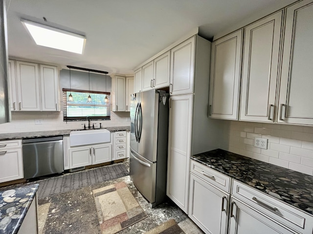 kitchen with stainless steel appliances, tasteful backsplash, dark stone countertops, and a sink