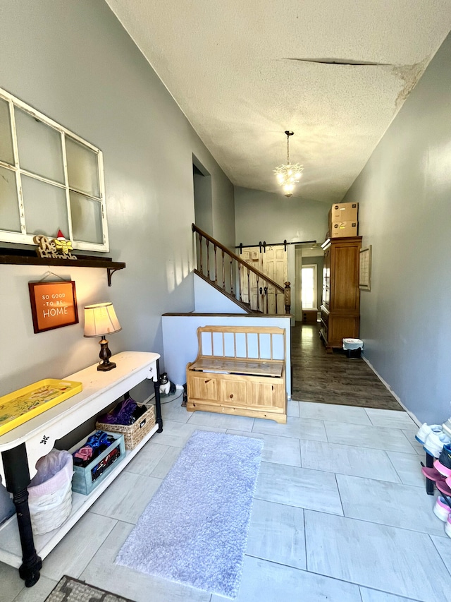 stairway with vaulted ceiling, a barn door, a textured ceiling, and a notable chandelier