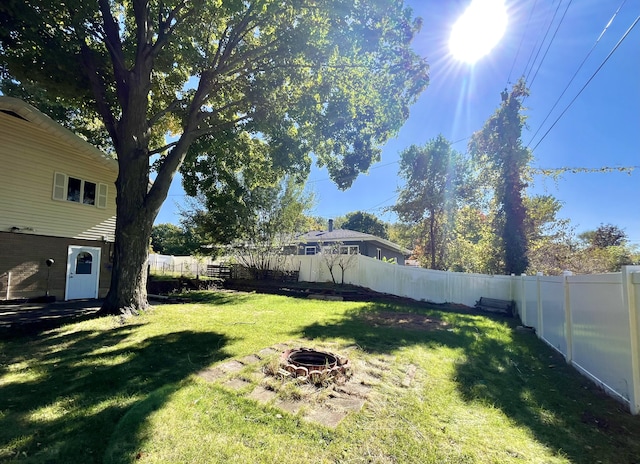 view of yard featuring a fenced backyard and a fire pit