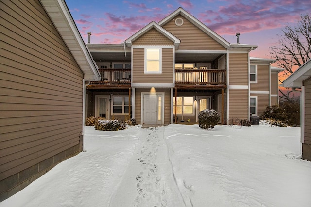 snow covered rear of property with a balcony