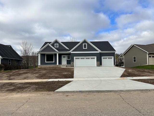 craftsman-style home with a garage, driveway, board and batten siding, and stone siding