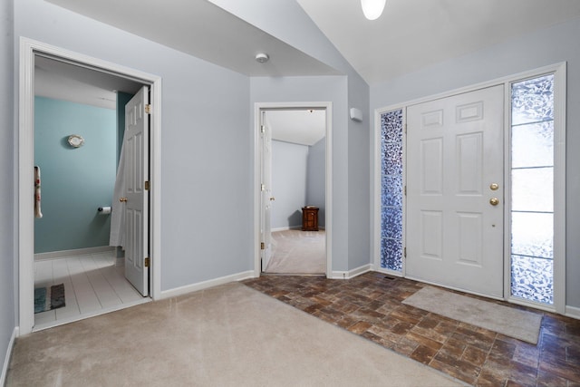 carpeted foyer featuring lofted ceiling and baseboards