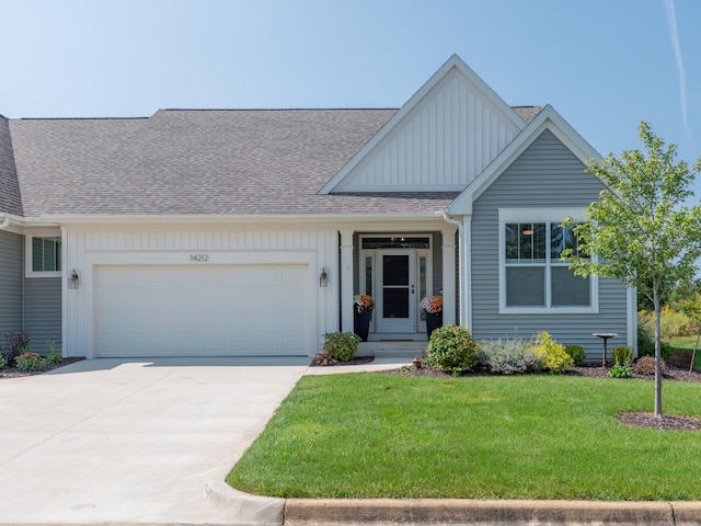 view of front facade featuring a shingled roof, a front lawn, concrete driveway, a garage, and board and batten siding