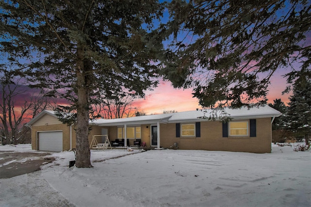 ranch-style home featuring an attached garage, covered porch, and brick siding