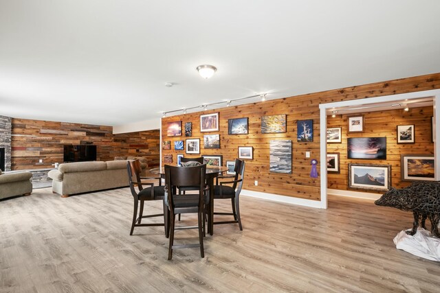 4588 Gordonshire NW, Grand Rapids, MI 49534 - dining area featuring track lighting, baseboards, a stone fireplace, wooden walls, and light wood-style flooring