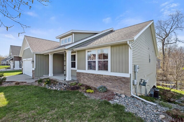 4588 Gordonshire NW, Grand Rapids, MI 49534 - view of front of house with roof with shingles, a front lawn, stone siding, a garage, and central AC unit