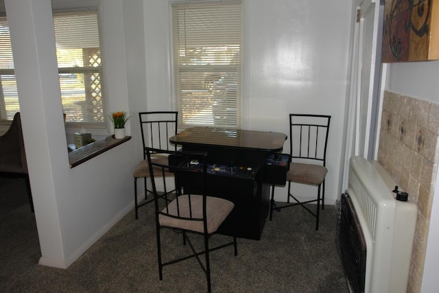 dining room featuring baseboards, carpet, tile walls, and heating unit