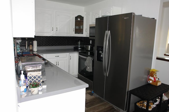 kitchen with dark wood-style flooring, white cabinets, appliances with stainless steel finishes, tasteful backsplash, and glass insert cabinets