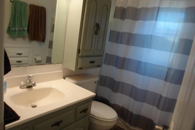 bathroom with curtained shower, vanity, and toilet