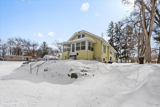 view of snow covered exterior featuring entry steps and a sunroom