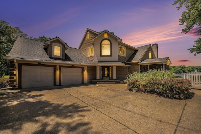 view of front of house with a garage, roof with shingles, and driveway