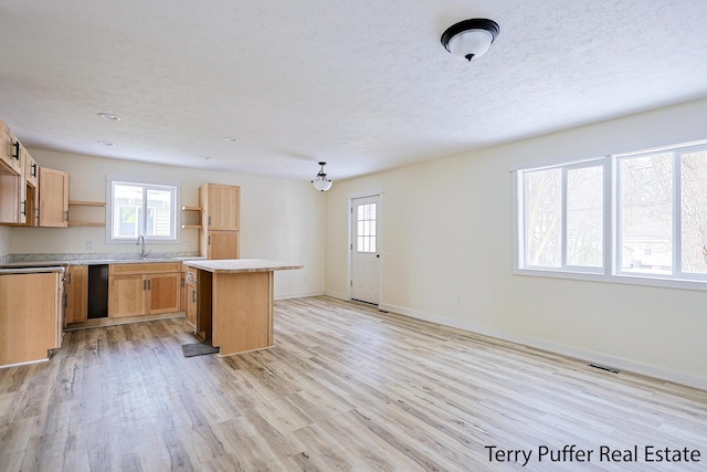 kitchen featuring a sink, a kitchen island, visible vents, light wood-type flooring, and open shelves