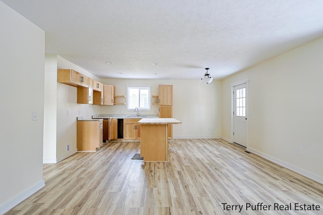 kitchen with a center island, light countertops, a textured ceiling, and light wood finished floors