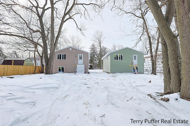 snow covered property featuring a garage and an outdoor structure