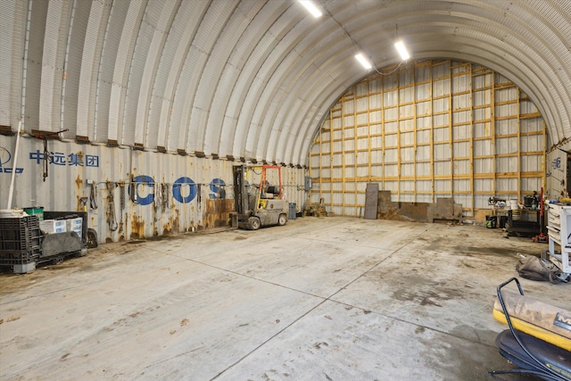 misc room with lofted ceiling, metal wall, and unfinished concrete floors
