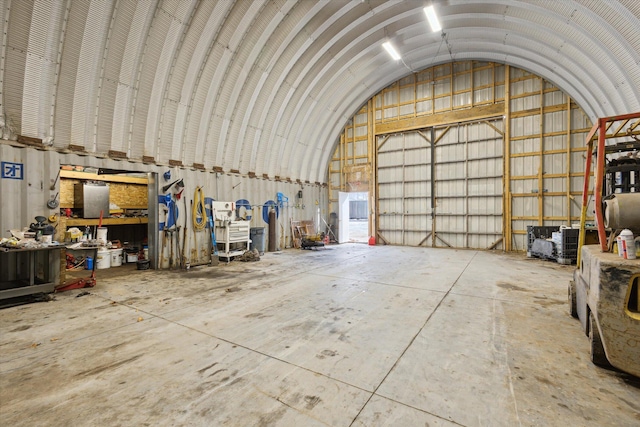 misc room with vaulted ceiling, metal wall, a garage, and concrete flooring