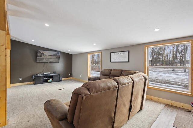 living room with a wealth of natural light, light carpet, lofted ceiling, and baseboards