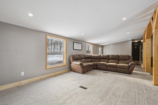 living room featuring recessed lighting, light colored carpet, visible vents, and a healthy amount of sunlight