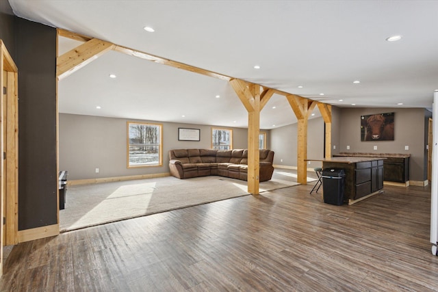 unfurnished living room featuring lofted ceiling, baseboards, wood finished floors, and recessed lighting