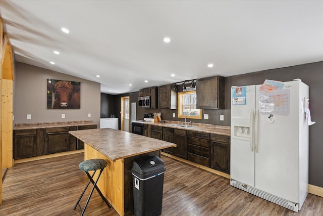 kitchen with white refrigerator with ice dispenser, stainless steel microwave, a center island, a sink, and range with electric stovetop