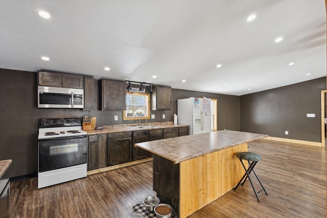 kitchen with white appliances, a kitchen island, light countertops, and a sink