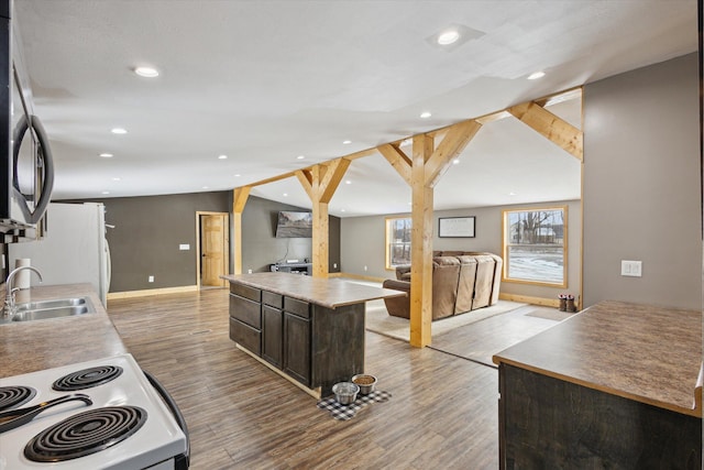 kitchen featuring white appliances, a sink, open floor plan, dark brown cabinets, and a center island