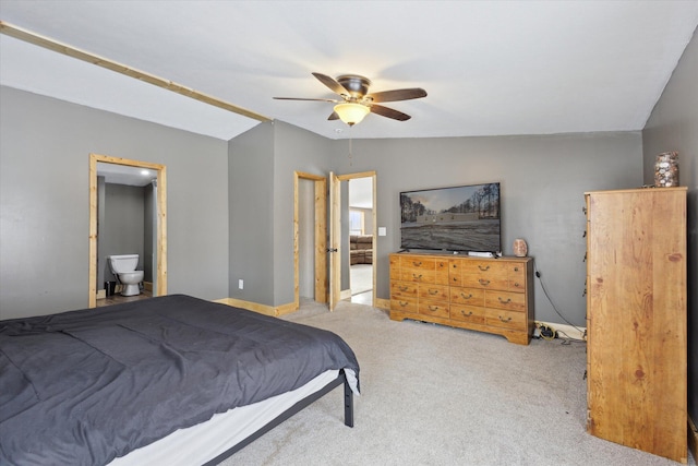 bedroom with light carpet, baseboards, a ceiling fan, ensuite bathroom, and vaulted ceiling