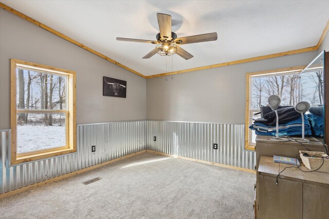 spare room featuring carpet floors, visible vents, vaulted ceiling, and ceiling fan