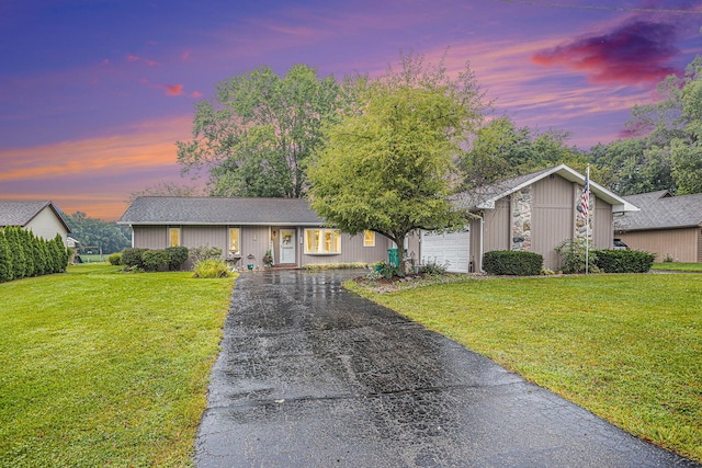 view of front of house featuring driveway, an attached garage, and a lawn