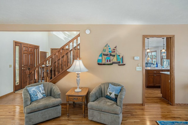 sitting room featuring light wood-type flooring, baseboards, and stairway