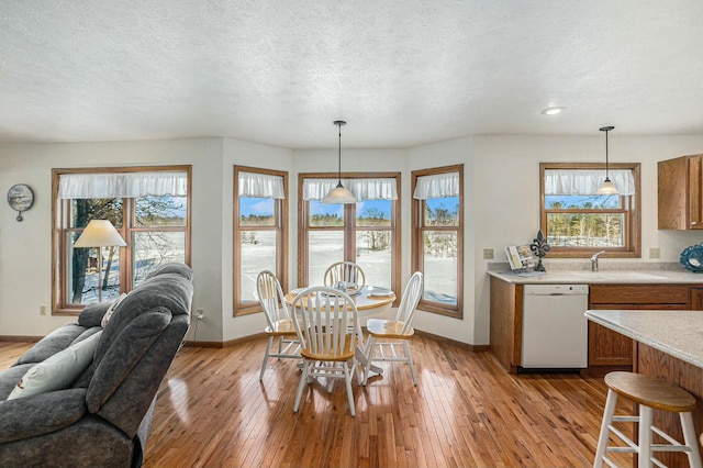 dining area with a textured ceiling, light wood finished floors, and baseboards