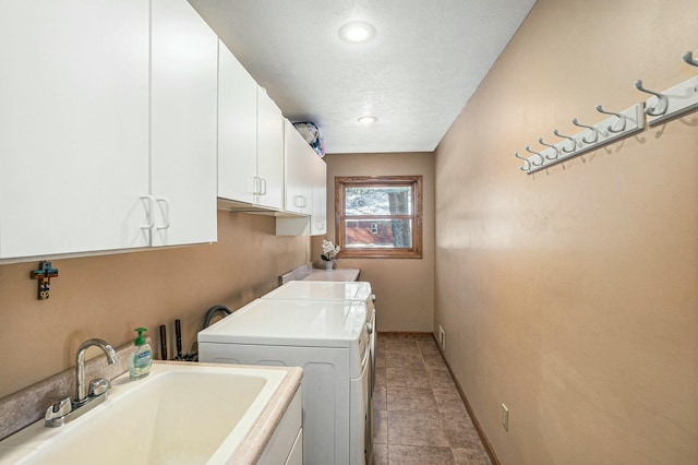 clothes washing area with baseboards, a sink, cabinet space, and washer and dryer