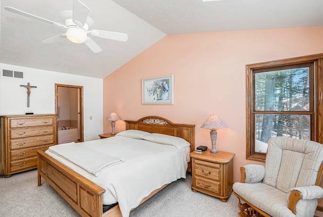 bedroom with lofted ceiling, light carpet, visible vents, a ceiling fan, and ensuite bath