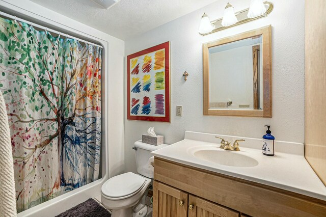 bathroom featuring a textured wall, toilet, curtained shower, a textured ceiling, and vanity