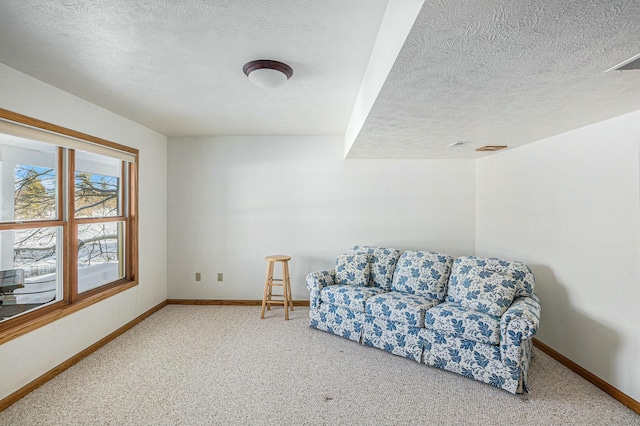 sitting room featuring a textured ceiling, carpet flooring, and baseboards