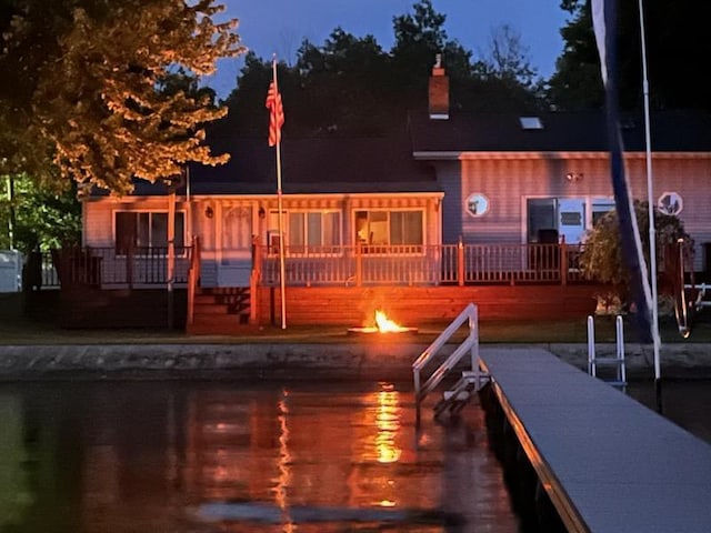 back of property at dusk with a chimney and a wooden deck