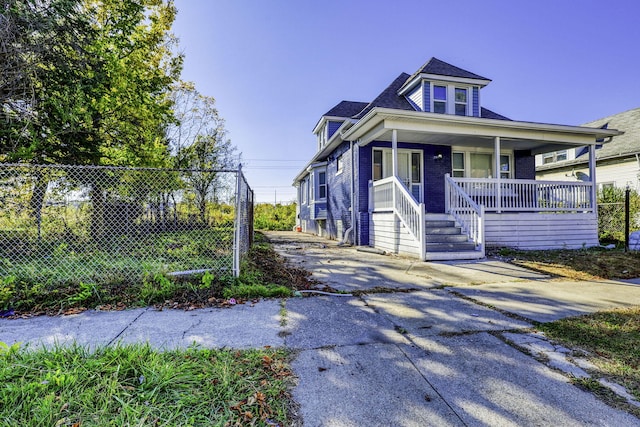 view of front of house with covered porch, brick siding, and fence