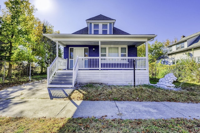 bungalow-style house featuring covered porch, fence, and brick siding