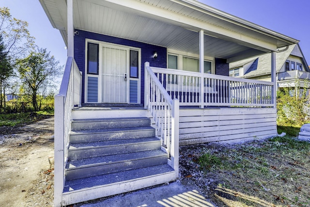 view of exterior entry with covered porch and brick siding