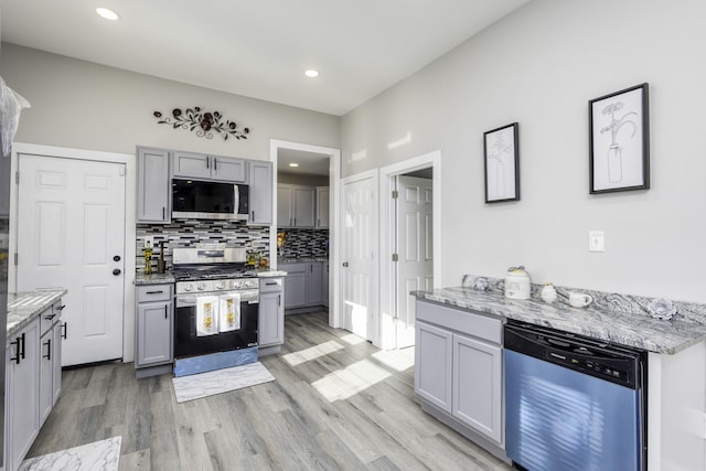 kitchen featuring appliances with stainless steel finishes, gray cabinets, decorative backsplash, and light stone counters