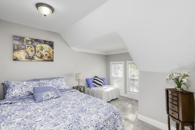 bedroom featuring light carpet, vaulted ceiling, and baseboards