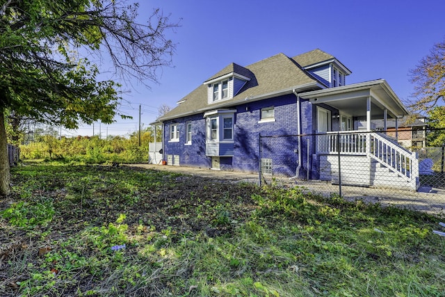 view of front facade with covered porch, fence, and brick siding