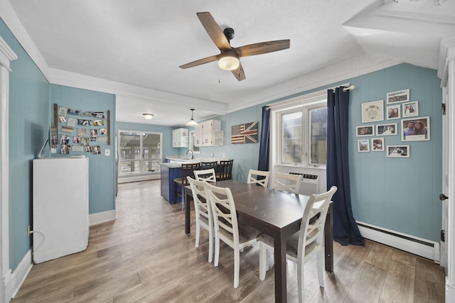 dining room featuring a wall unit AC, ceiling fan, a baseboard heating unit, and wood finished floors