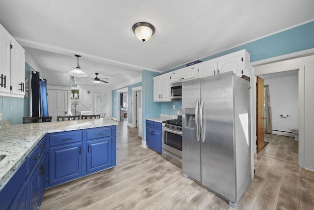 kitchen featuring light wood finished floors, blue cabinetry, stainless steel appliances, hanging light fixtures, and white cabinets