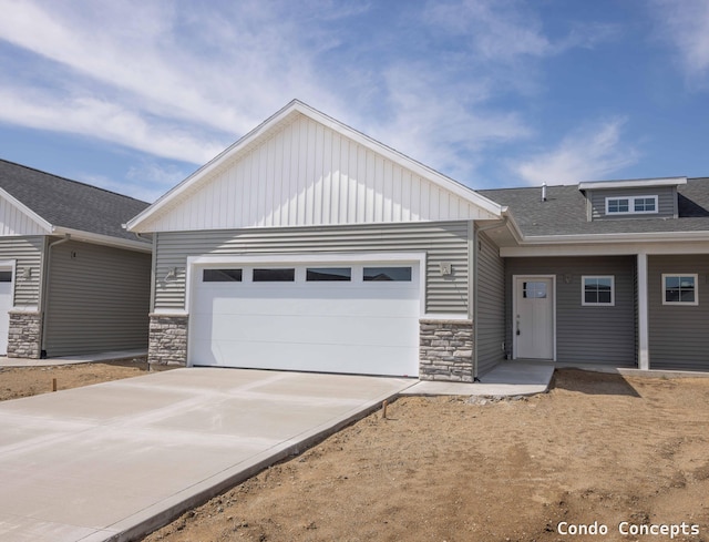 6625 Shoreside Ct SE, Grand Rapids, MI 49548 - view of front of house featuring stone siding, a garage, driveway, and roof with shingles