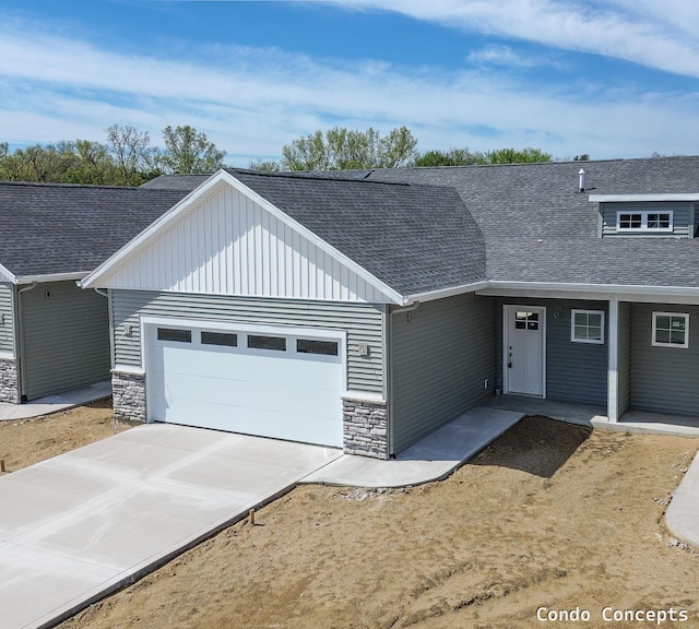 6625 Shoreside Ct SE, Grand Rapids, MI 49548 - view of front of house featuring stone siding, roof with shingles, a garage, driveway, and board and batten siding
