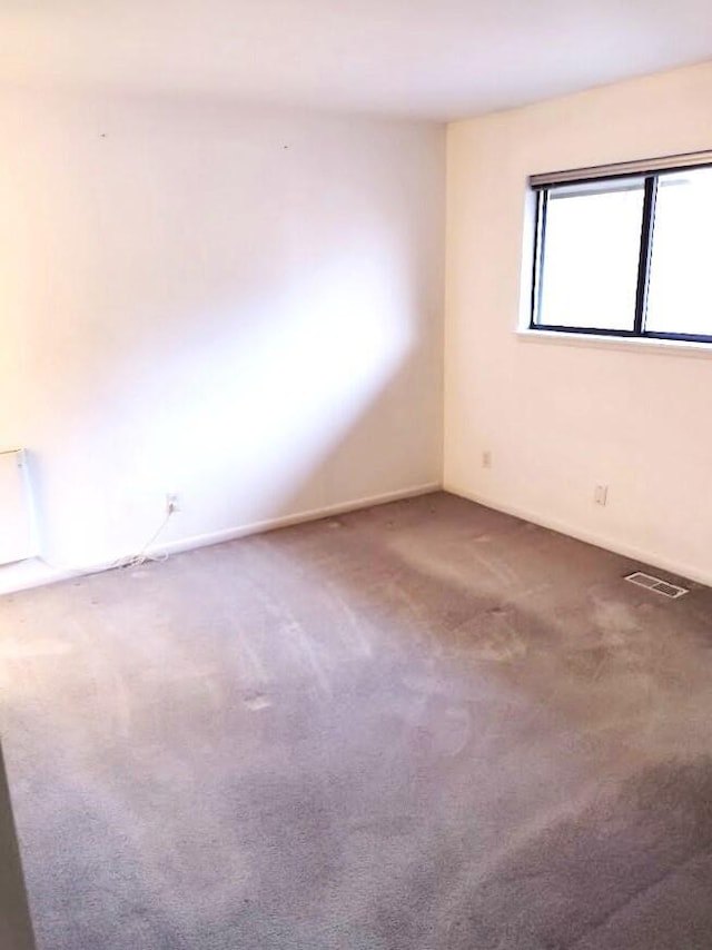 carpeted empty room featuring visible vents and baseboards