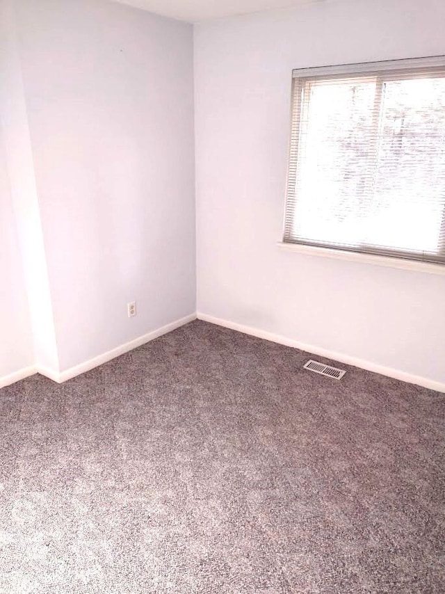 empty room with baseboards, visible vents, and carpet flooring