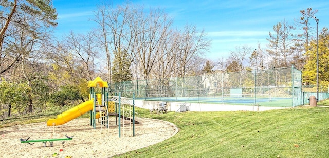 community playground featuring a tennis court, a lawn, and fence