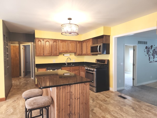 kitchen featuring brown cabinets, visible vents, stainless steel appliances, and a sink